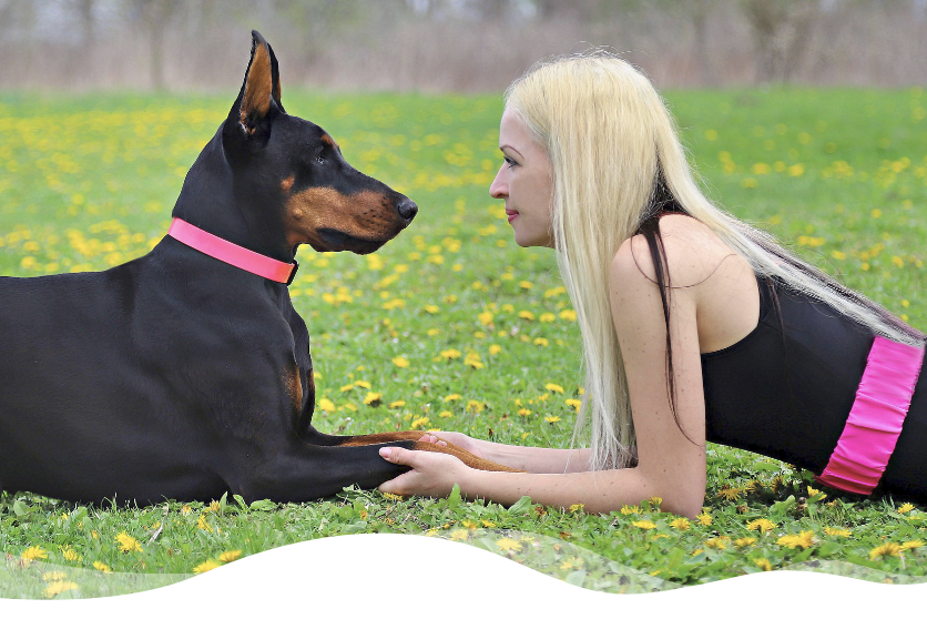 Großer, schwarzer Hund und Frau liegen auf der Wiese.